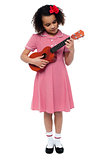Preschool cute girl playing a guitar