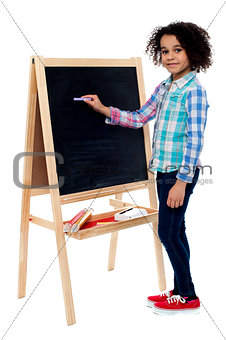Happy schoolchild writing on blackboard