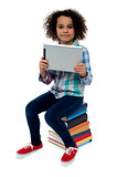 Adorable kid with tablet pc sitting on books