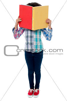 School girl hiding her face with a book