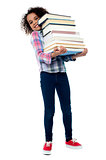 Cute cheerful child carrying stack of books