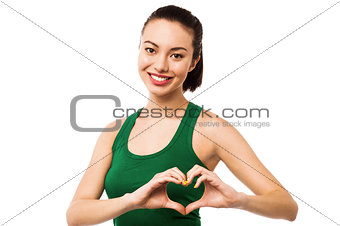 Pretty teenager making heart symbol with hands