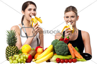 Young smiling girls eating banana