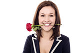 Young female holding rose between her teeth