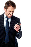 Angry businessman looking at his phone