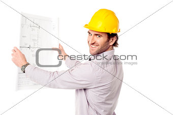 Smiling construction engineer reviewing blueprint