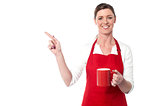 Female chef with coffee mug pointing away