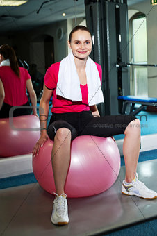 Pretty fit woman sitting on pink swiss ball