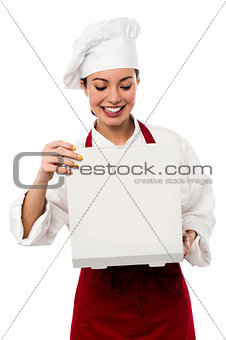 Smiling pretty chef opening pizza box