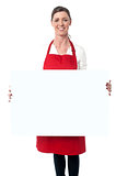 Lady wearing apron holding white blank ad board