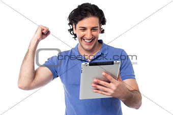 Excited young man holding touch pad device