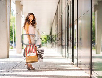Brown-haired woman smiling holding colourful shopping bags