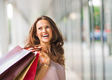 Brown-haired, happy, smiling woman holding up shopping bags