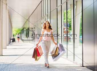 Brown-haired woman walking in sunlight on a shopping spree