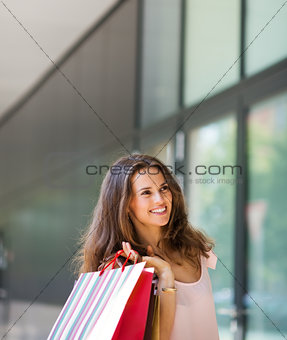 Smiling woman shopping, holding up colourful shopping bags