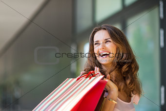 Happy woman out shopping, holding up colourful shopping bags
