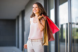Smiling woman with three shopping bags looking into distance