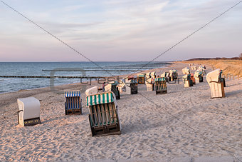 Beach chairs with dunes at sunset