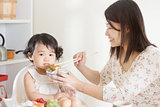 Asian mother feeding child