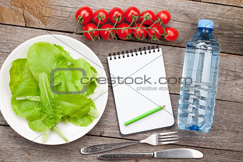 Fresh healthy salad, tomatoes, water bottle and notepad for copy