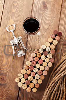Wine bottle shaped corks, glass of red wine and corkscrew
