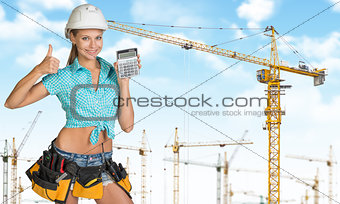 Smiling young woman in hard hat holding calculator
