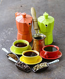 green, black coffee beans and different utensils for boiling coffee (grinder, kettle, cezve)