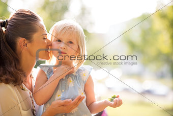 Mother whispering to her daughter in the sunshine in a city park