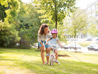 Mother teaching her daughter how to ride a bicycle in a park