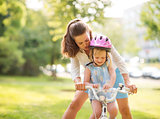 Mother shows daughter how to ride a bike holding handlebars