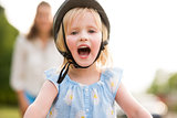 Blonde, blue-eyed, smiling and happy girl wearing a bike helmet