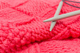 red knitted fabric, two knitting spokes close-up