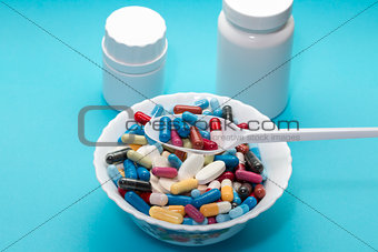 Different pills on a plate with two bottle and spoon