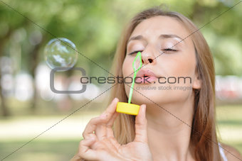 young woman blowing soap bubbles in the air.