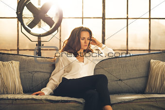 Elegant woman sitting on a sofa, crossing legs, in a loft