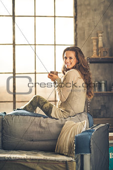 Woman smiling looking over shoulder holding cup in loft