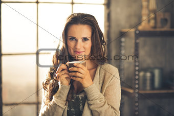 Head and shoulder shot of woman holding cup in loft apartment
