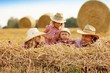 young family on haystacks in cowboy hats