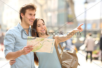 Couple of tourists consulting a city guide searching locations