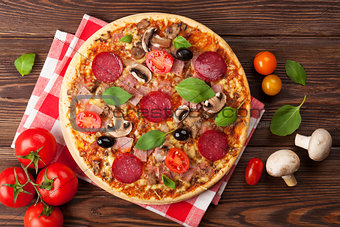 Italian pizza with pepperoni, tomatoes, olives and basil