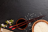 Japanese sushi chopsticks over soy sauce bowl, rice and sakura b