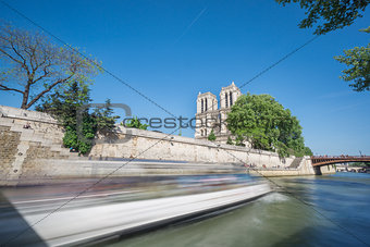 Notre dame and Seine river with tourist boat, long exposure