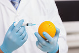 Scientist holding orange and injecting fluid with syringe