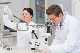 Scientists working with microscope and test tube