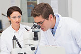 Scientists looking attentively in microscope