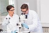 Scientists looking attentively in microscope