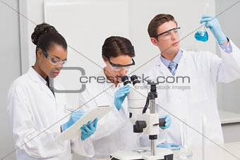 Scientists working attentively with microscope and beaker