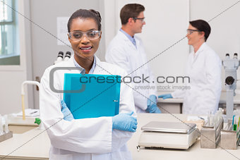 Scientist smiling at camera while colleagues talking together