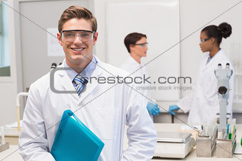 Scientist smiling at camera while colleagues talking together