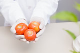 Scientist with protective gloves holding tomatoes